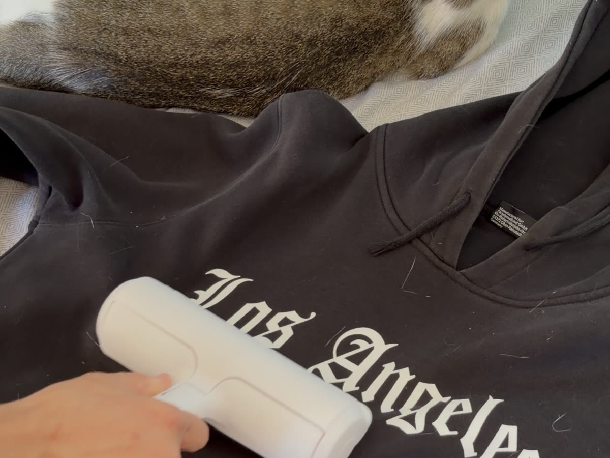 Pasando el rodillo por una sudadera con pelo de gato